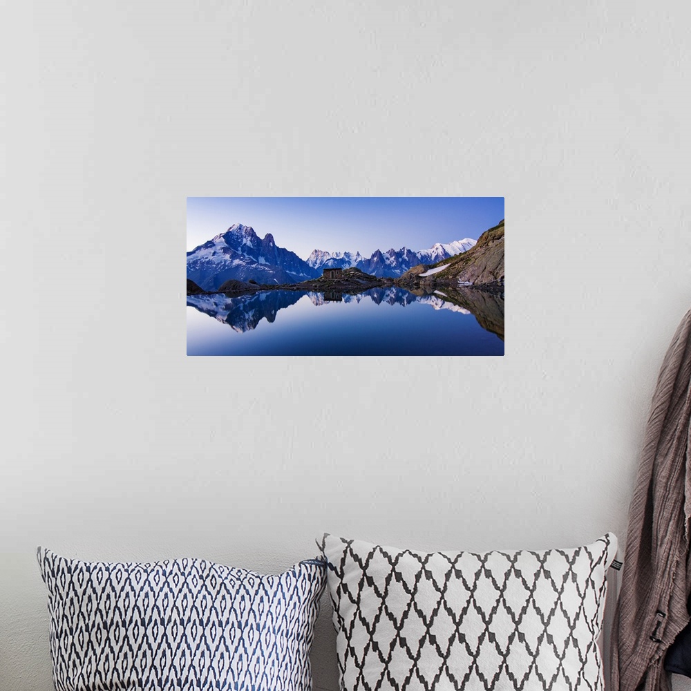 A bohemian room featuring A panoramic view of a blue mountain range with a crystal blue lake at the base reflecting the range.