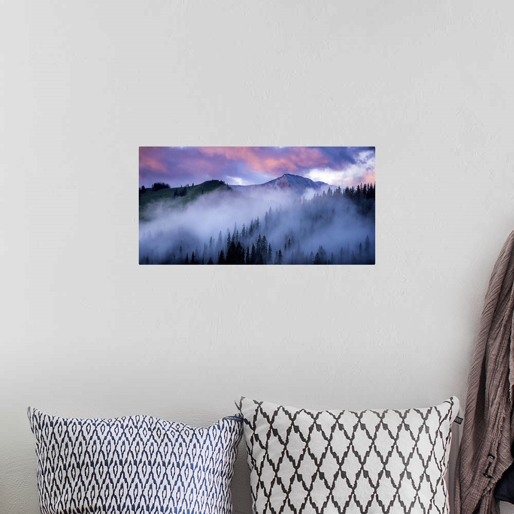 A bohemian room featuring A photograph of mountain under dramatic clouds illuminated by the sunset.