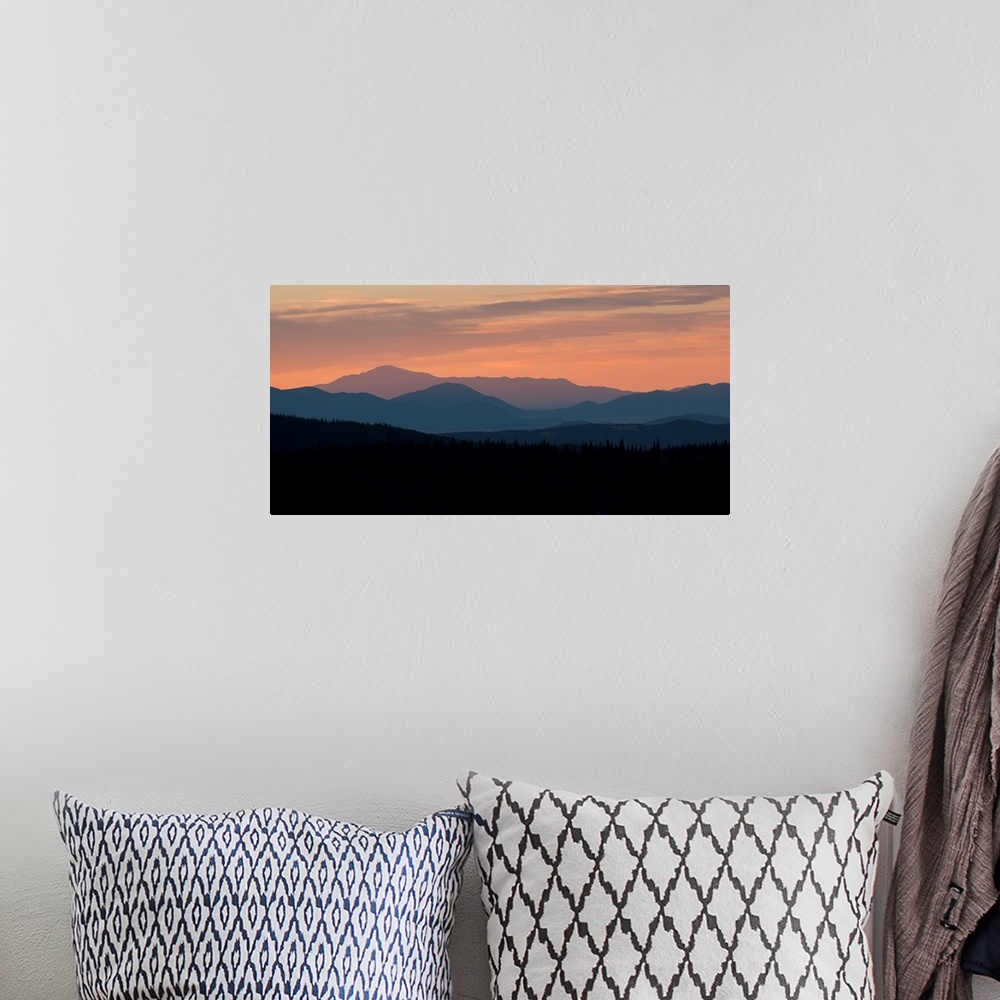 A bohemian room featuring Landscape photograph of a silhouetted mountain range at sunset.