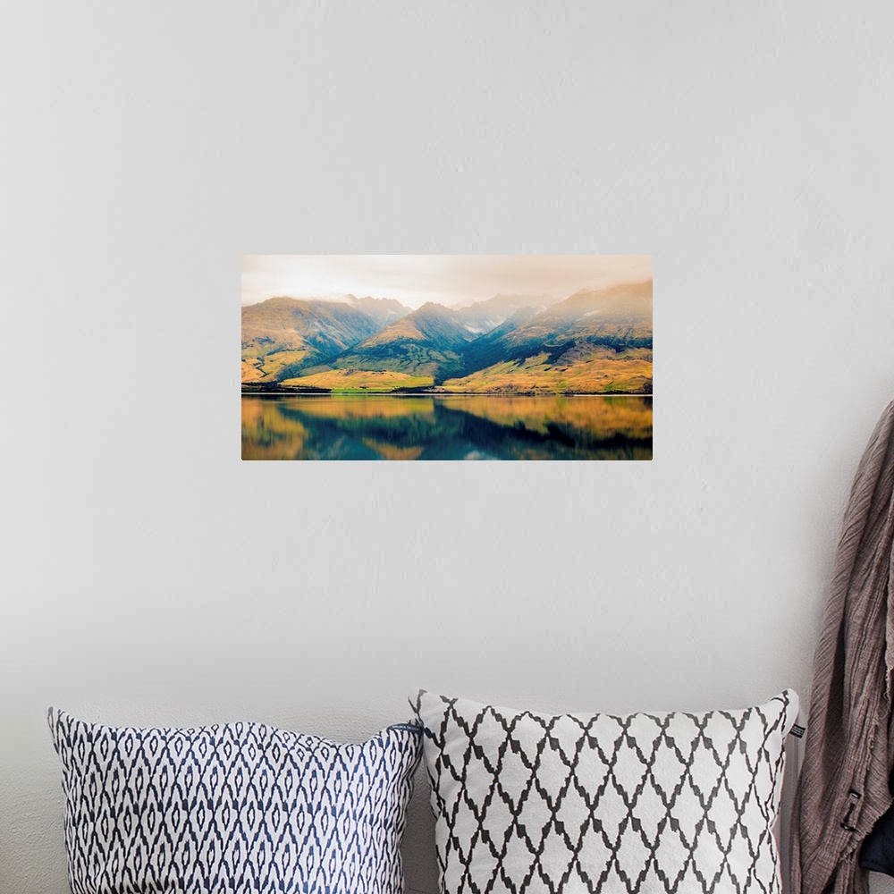 A bohemian room featuring Landscape photograph of a lake with Autumn covered mountains in the background and a foggy top.