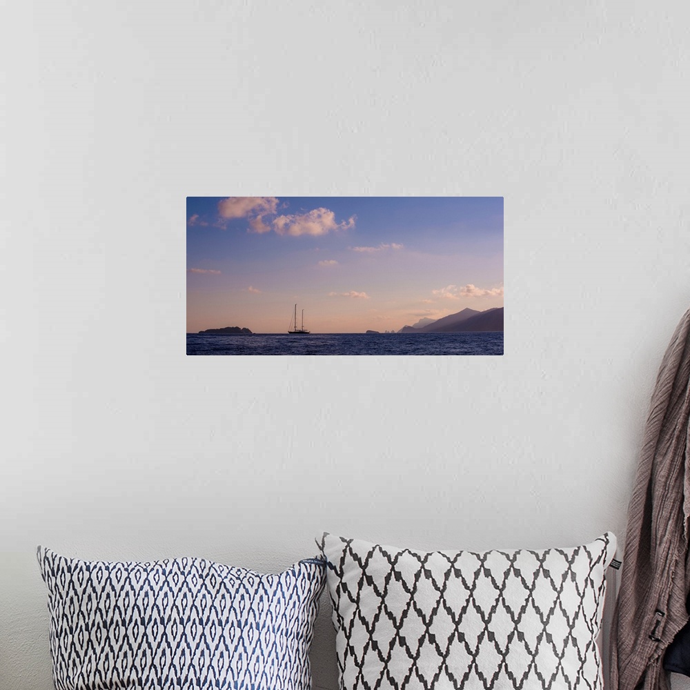 A bohemian room featuring Photograph of a single sailboat in the middle of the ocean with silhouettes of mountains in the d...