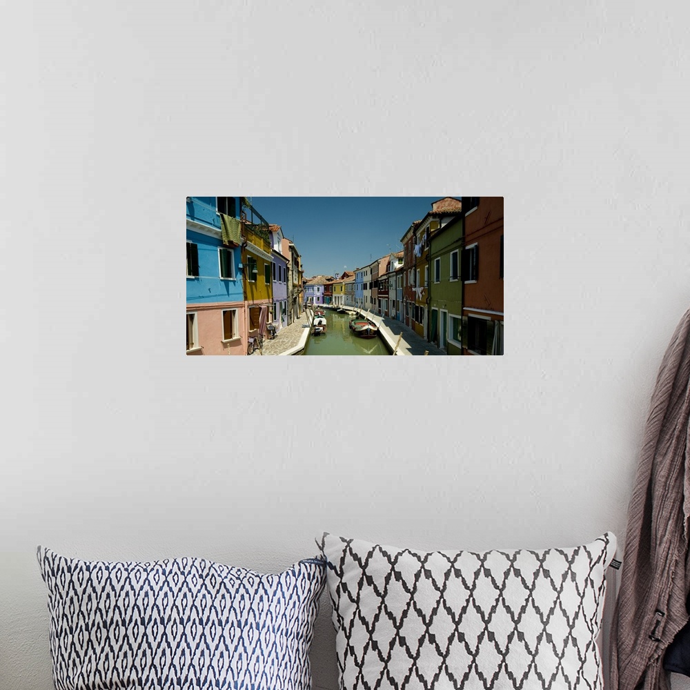 A bohemian room featuring Colorful buildings line either side of a canal in Italy.