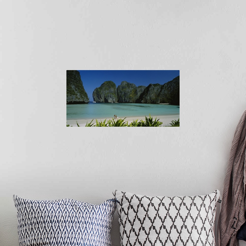 A bohemian room featuring A breathtaking photograph of a beach in Thailand surrounded by mountains with a couple at the edg...