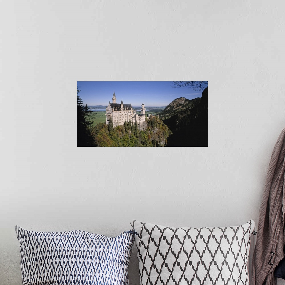 A bohemian room featuring A landscape photograph of an elegant caste build on top of a steep, tree covered hill.
