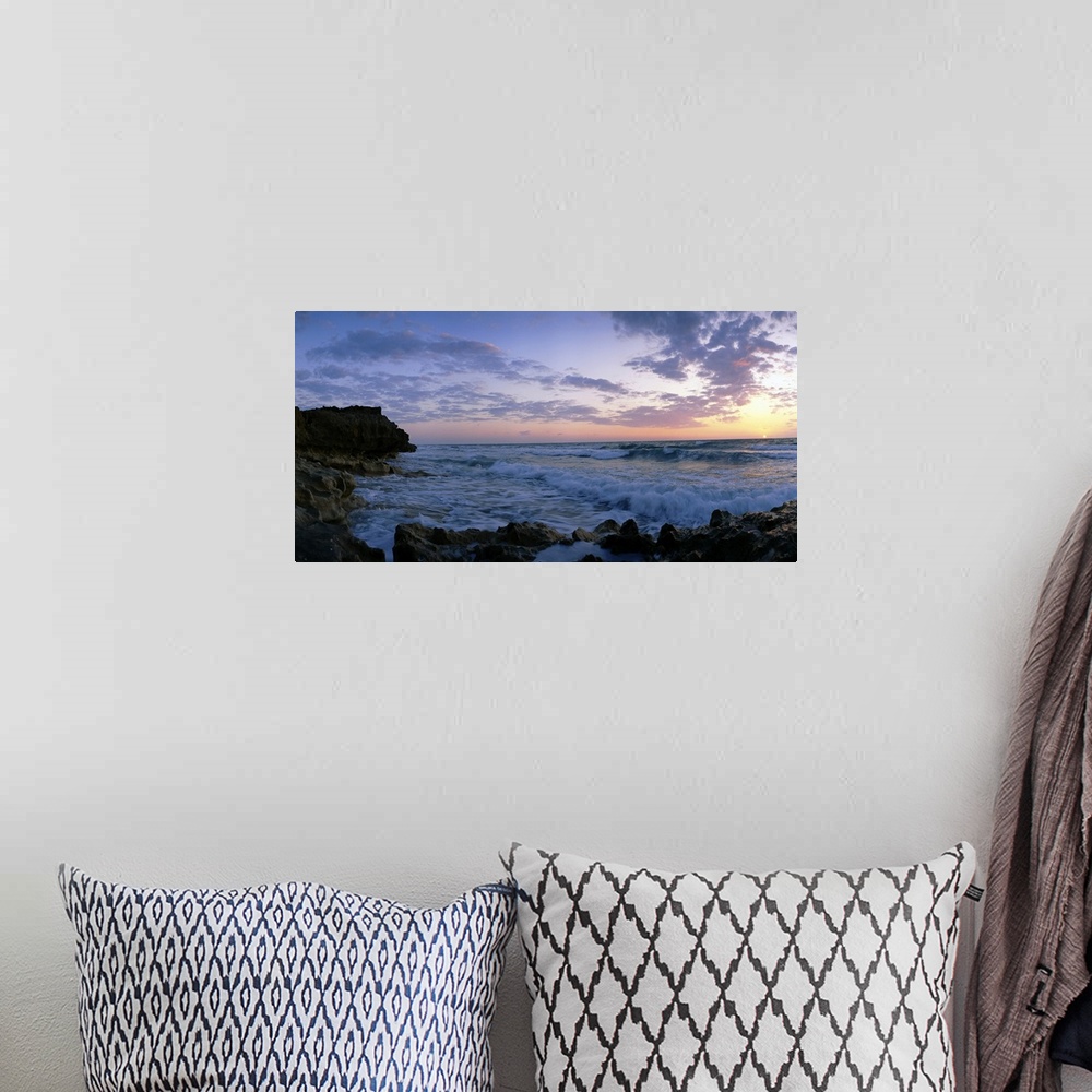 A bohemian room featuring Oversized artwork of a photograph looking out into the ocean as waves crash onto the rock formati...