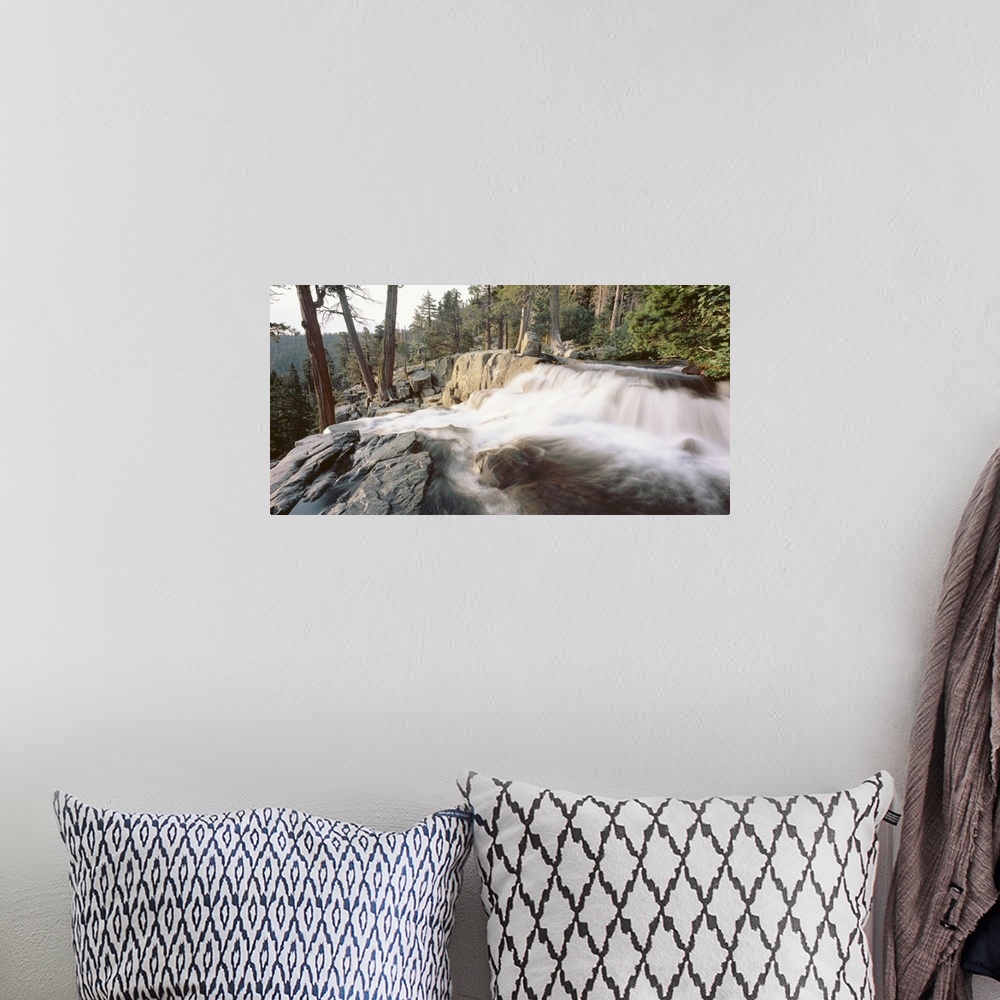 A bohemian room featuring A picture that has been taken of a waterfall flowing over large rocks and surrounded by a dense f...