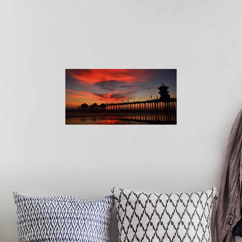 A bohemian room featuring Huntington Beach Pier, California, at sunset, with bright red clouds above.