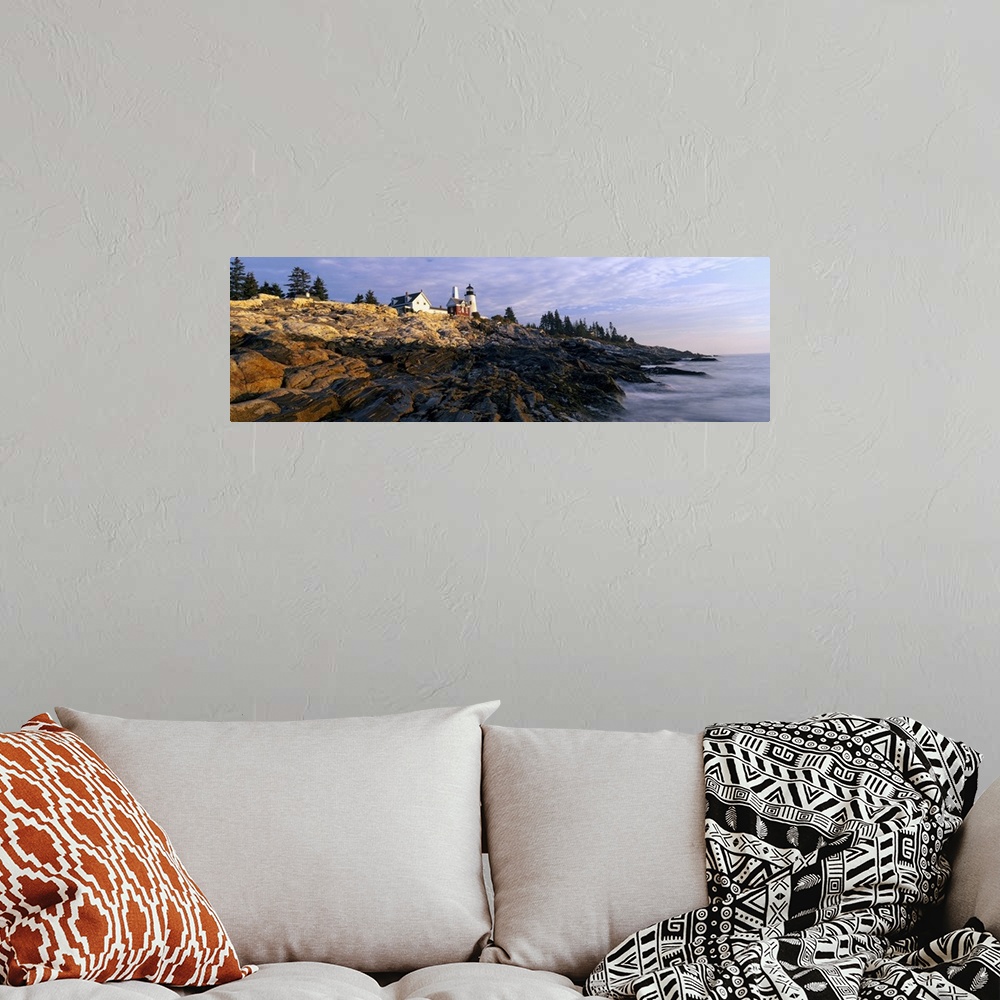 A bohemian room featuring A large panoramic photograph taken from sea level and looking up at a lighthouse. Rocks take up m...