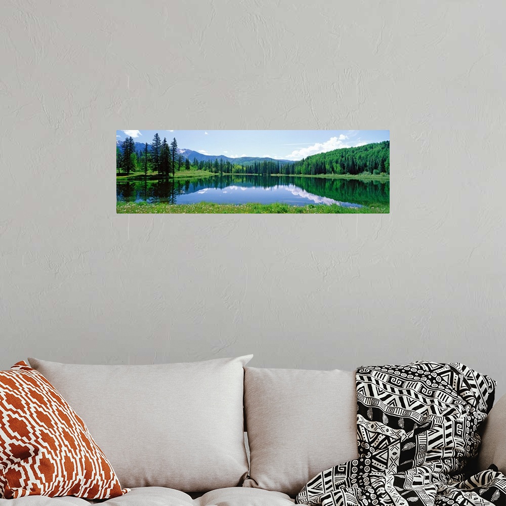 A bohemian room featuring The still waters of a Colorado lake reflect the trees and clouds in this panoramic landscape phot...