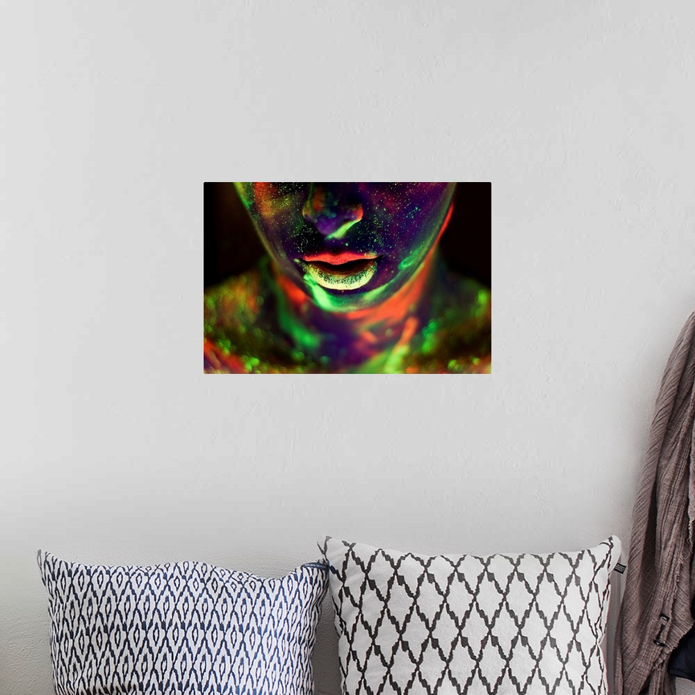 A bohemian room featuring A woman's face and neck covered in glow-in-the-dark paint in neon colors.