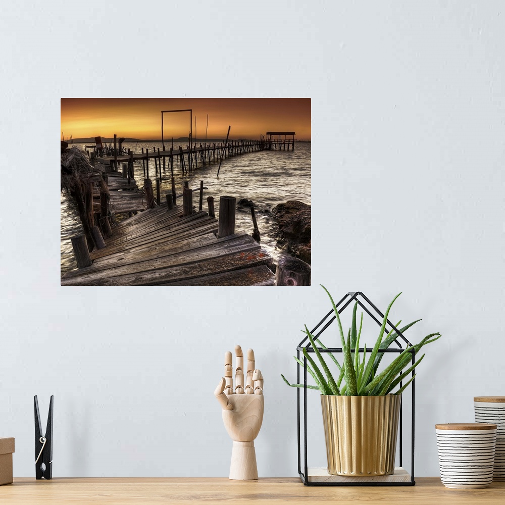 A bohemian room featuring A decaying wooden pier in Carrasqueira, Spain, at sunset.