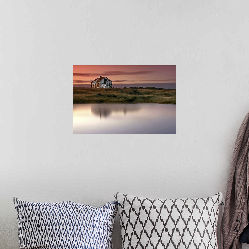 A bohemian room featuring An abandoned farm house on the grassy shore by a lake in Iceland, at sunrise.