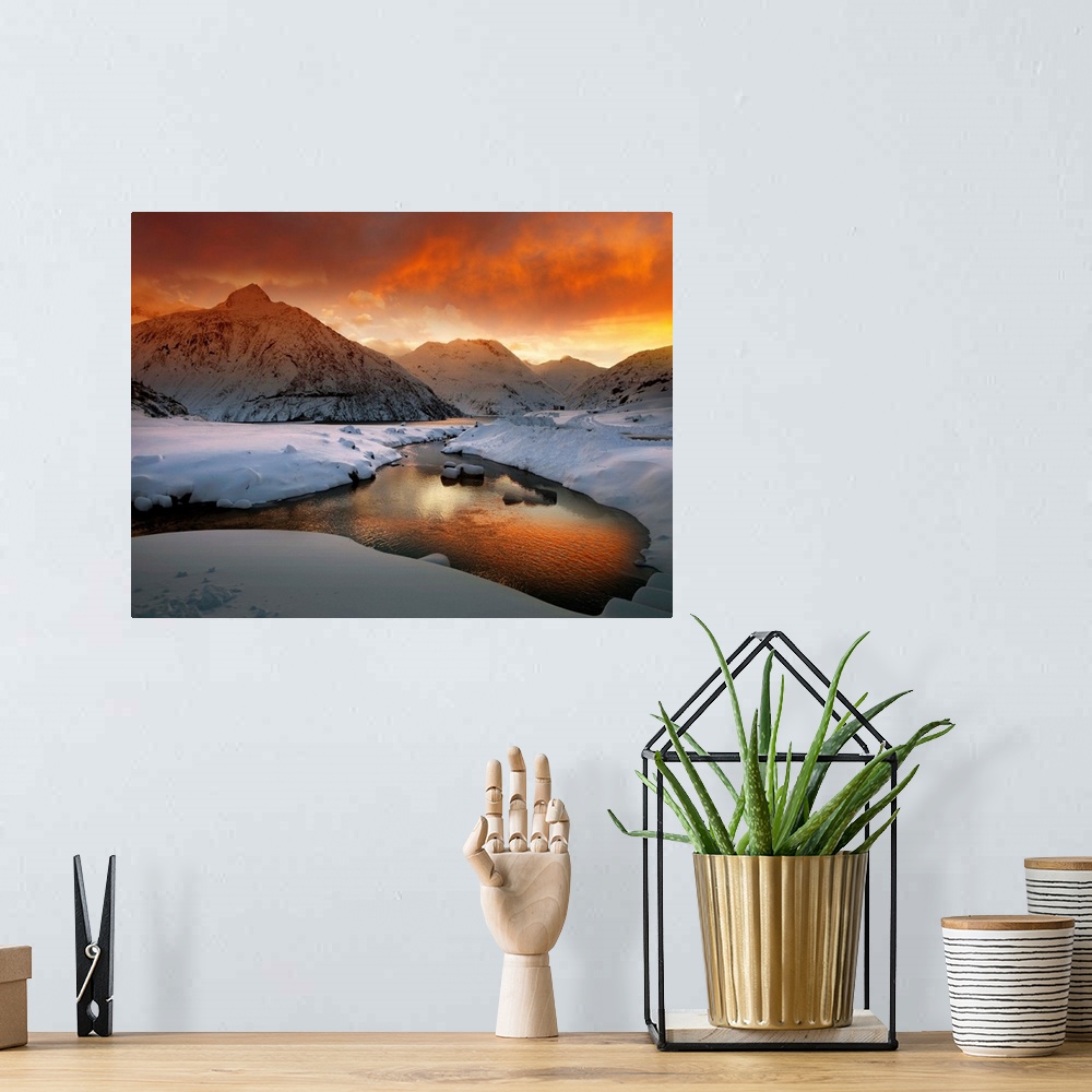 A bohemian room featuring A river in a snowscape reflecting the orange color of the sunrise, in the Austrian Alps.