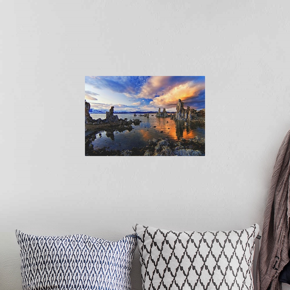 A bohemian room featuring A photograph of jagged rough looking rocks in a lake under dramatic clouds.