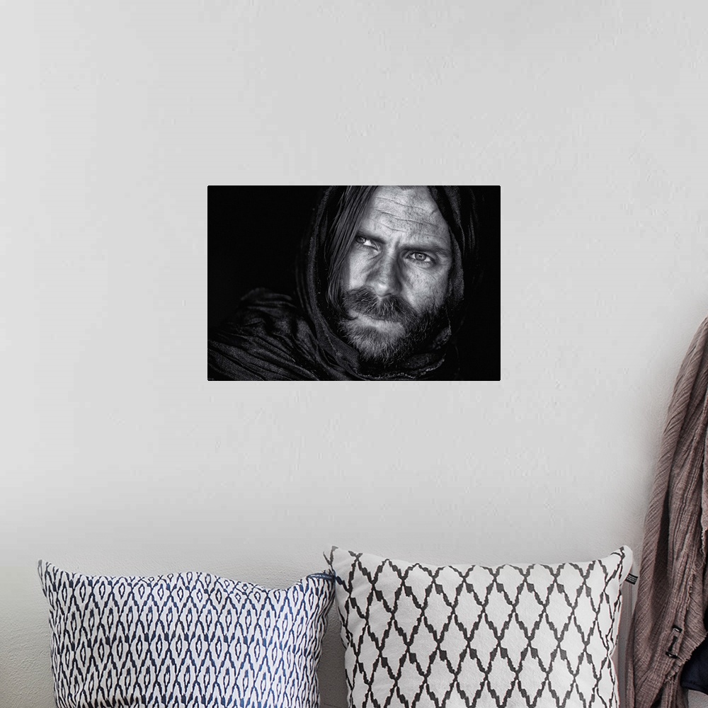 A bohemian room featuring Portrait of a man with a beard and long hair, wearing a hood.