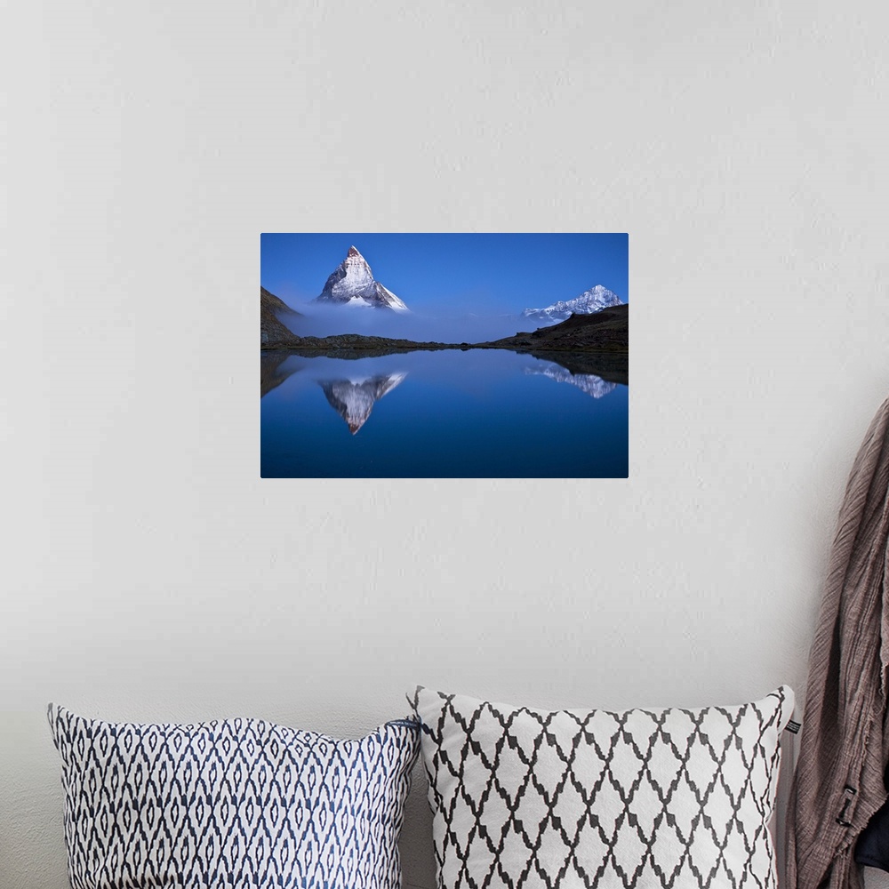 A bohemian room featuring A photograph of the Swiss Alps with the base of the Matterhorn covered in fog.