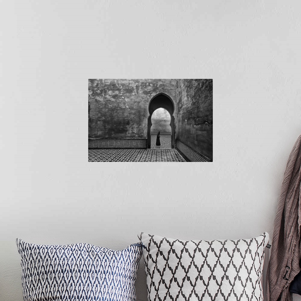 A bohemian room featuring A black and white photograph of a man passing by an archway.