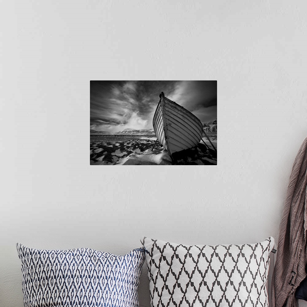 A bohemian room featuring A black and white photograph of a row boat on the shore of an Icelandic beach.