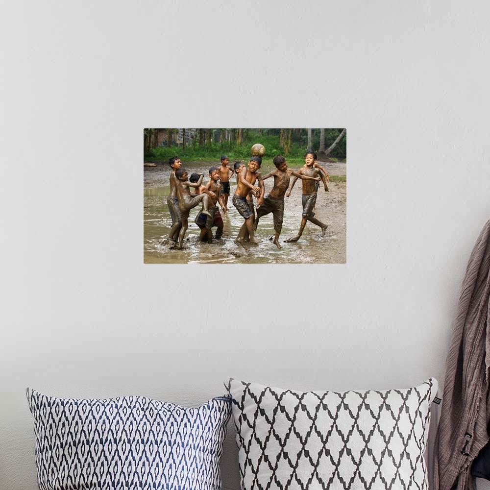 A bohemian room featuring A group of young boys playing soccer in muddy water.