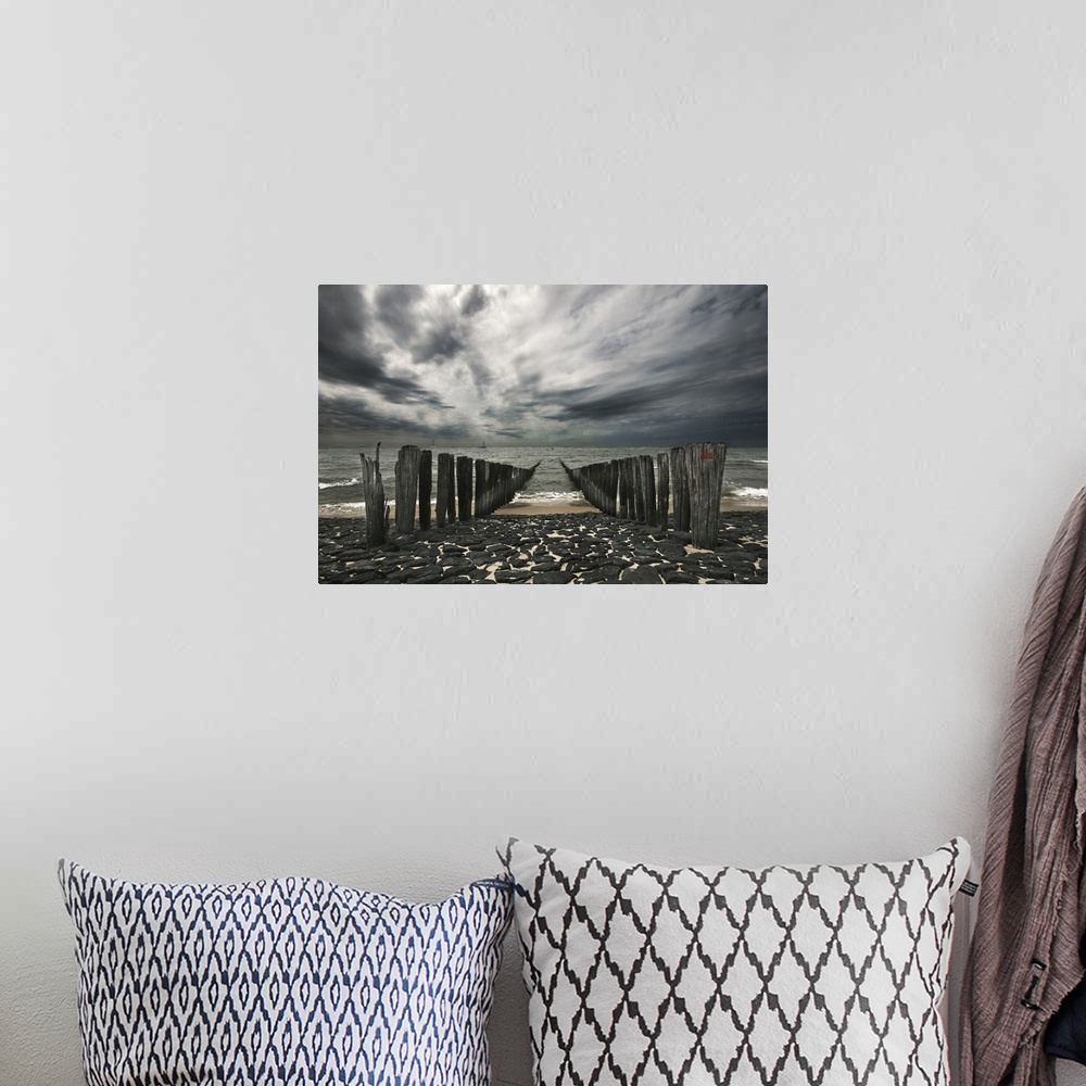 A bohemian room featuring Landscape photograph of the ocean and the remains of a pier on an overcast, gloomy day.