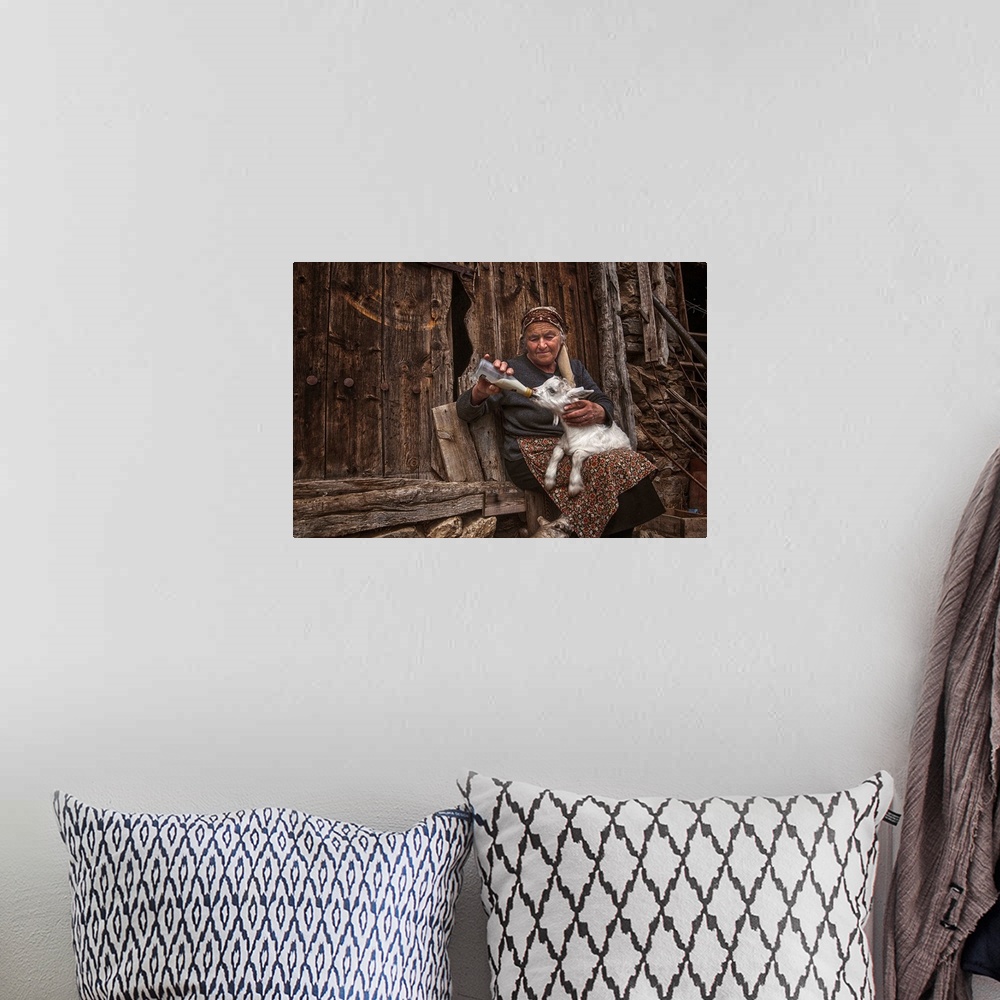 A bohemian room featuring A portrait of an old woman feeding a young goat.
