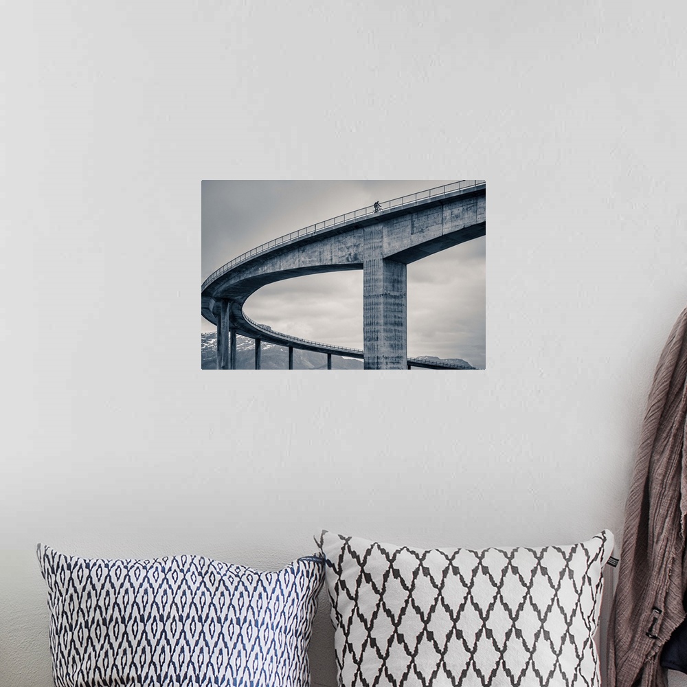 A bohemian room featuring A biker riding across the top of a tall concrete bridge, Norway.