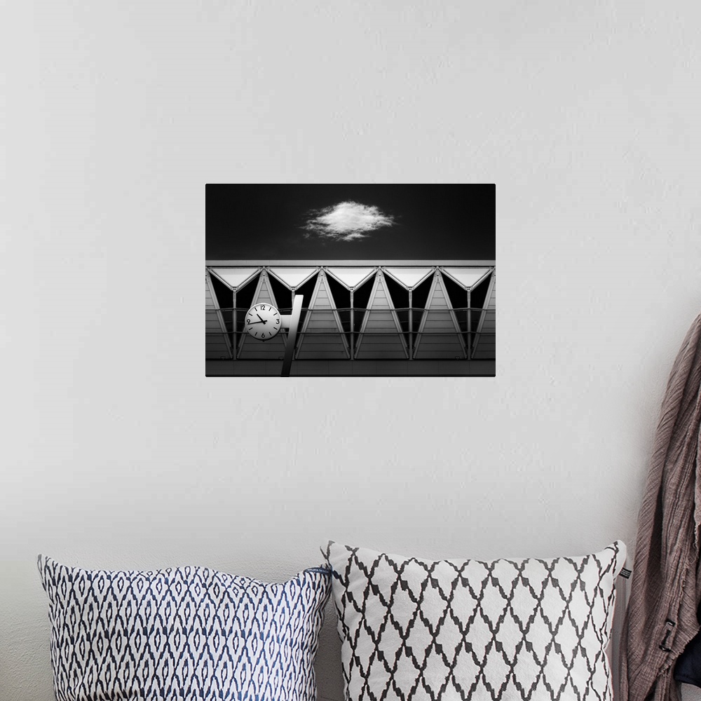 A bohemian room featuring Black and white abstract photograph of a clock hung in front of unique triangular windows with a ...