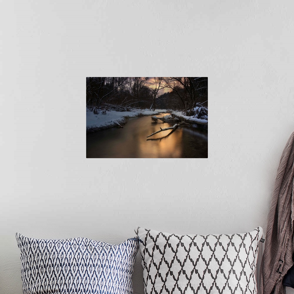 A bohemian room featuring A serene river reflecting evening light in a snowy forest in the winter.