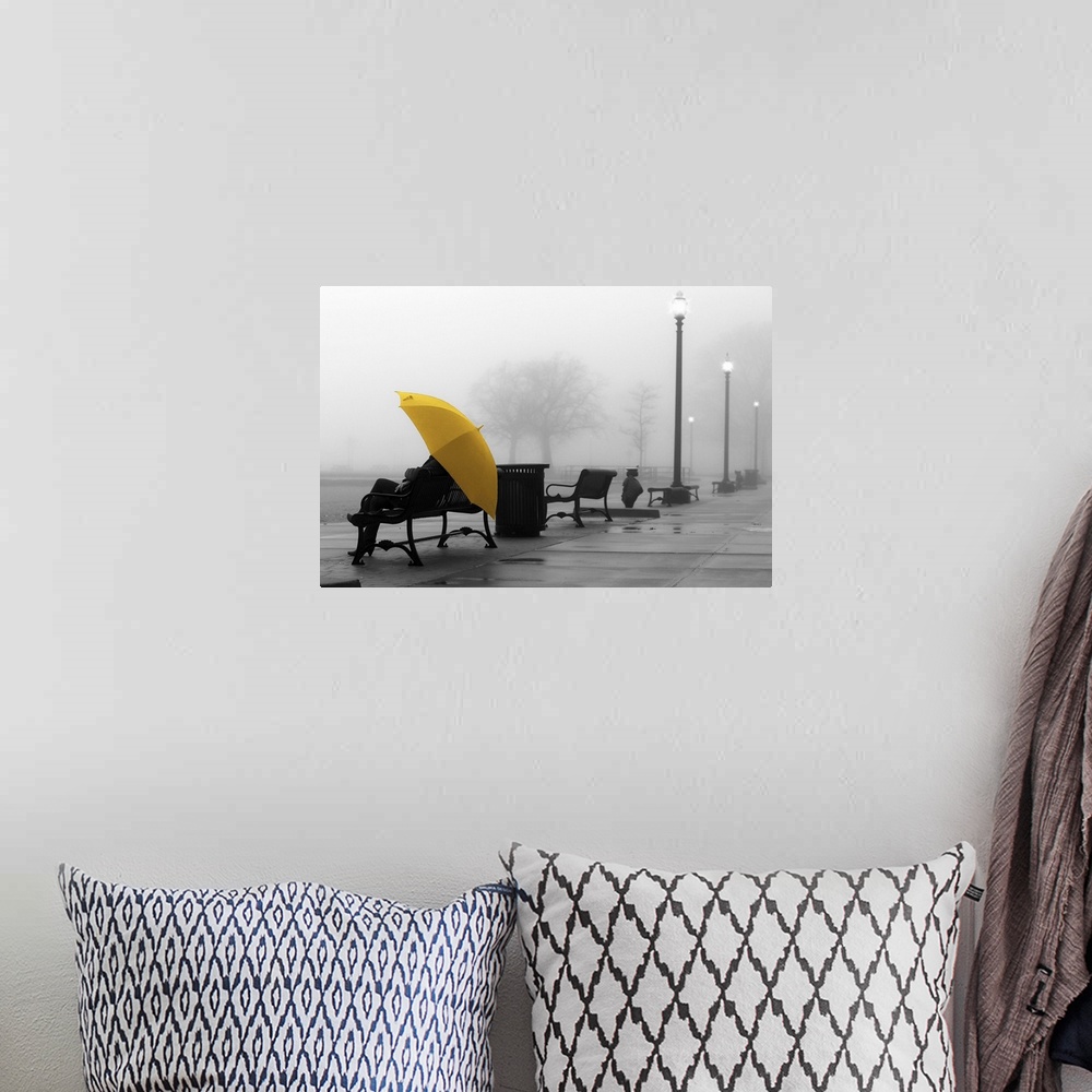 A bohemian room featuring A black and white photograph of a person with a colorized yellow umbrella sitting on a bench on a...