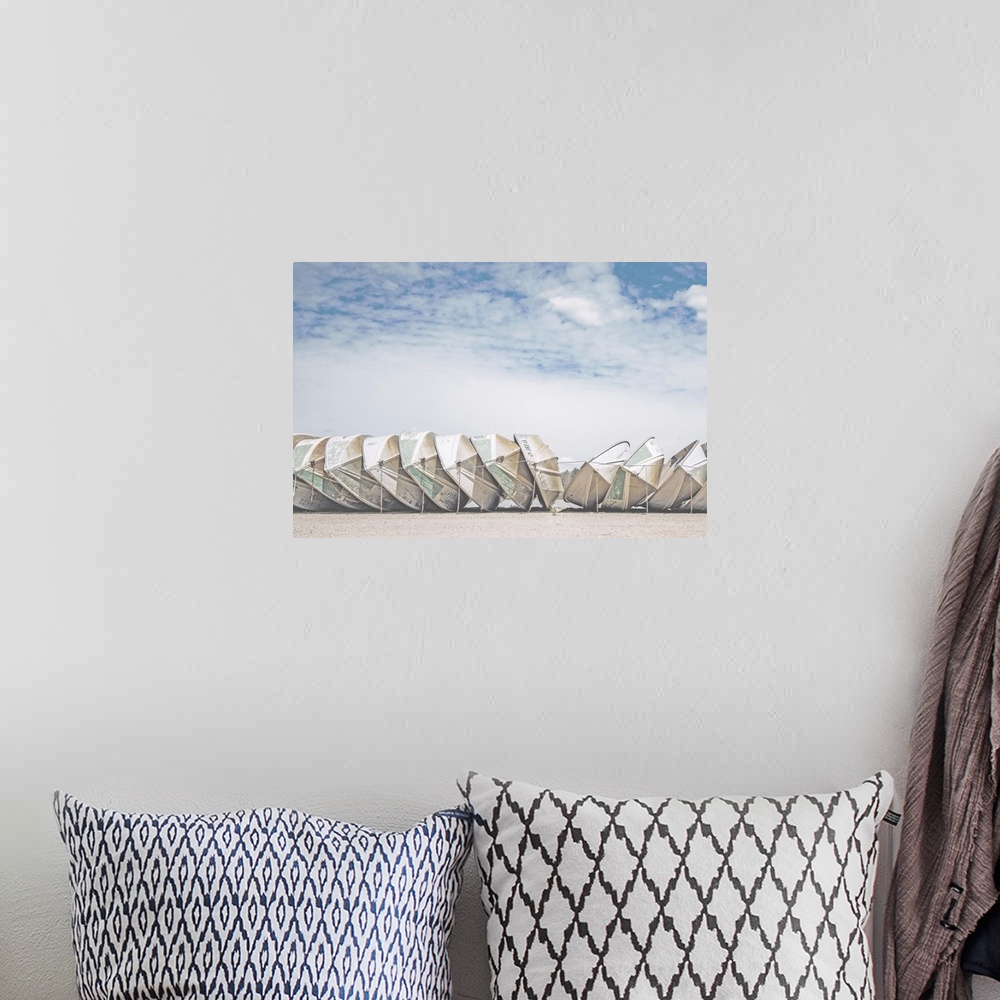 A bohemian room featuring A fine art photograph of a row of identical small boats leaned against each other, with a very co...