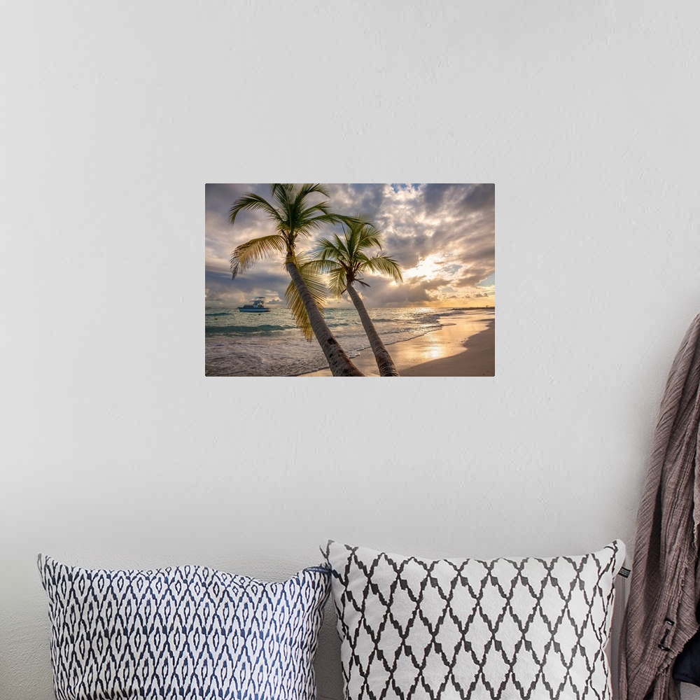 A bohemian room featuring Close-up of palm tree with a yacht moored off shore and the turquoise water and foamy surf rolls ...