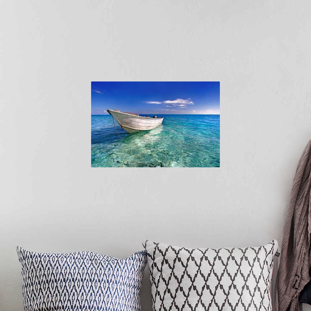 A bohemian room featuring An image print of a wooden boat floating in a crystal clear ocean.