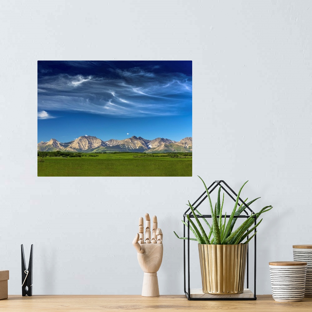 A bohemian room featuring Mountain range with wispy white clouds, blue sky and green field in the foreground