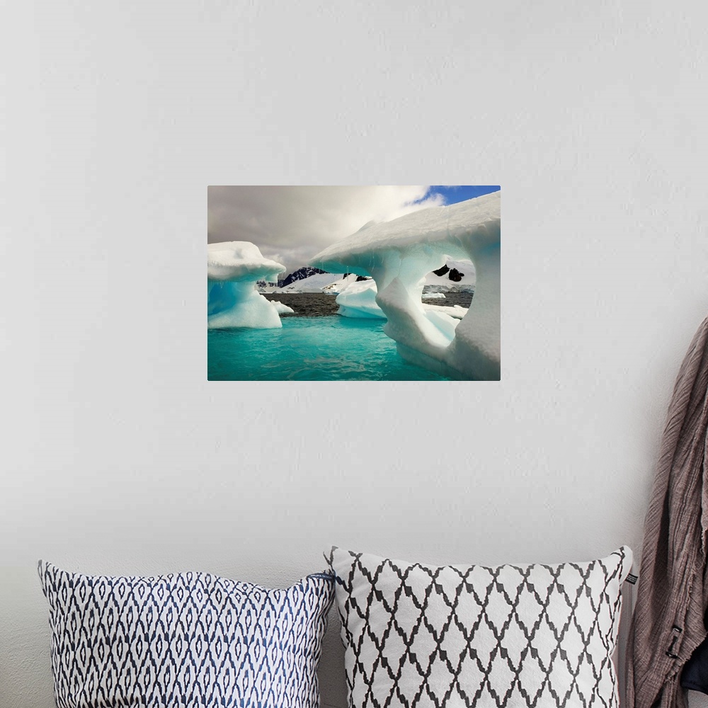 A bohemian room featuring Sculpted icebergs under clouds near the shore of Couverviller Island.