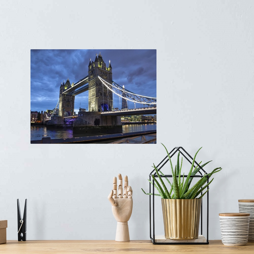 A bohemian room featuring Tower Bridge illuminated at dusk and reflected in the tranquil water of the River Thames; London,...
