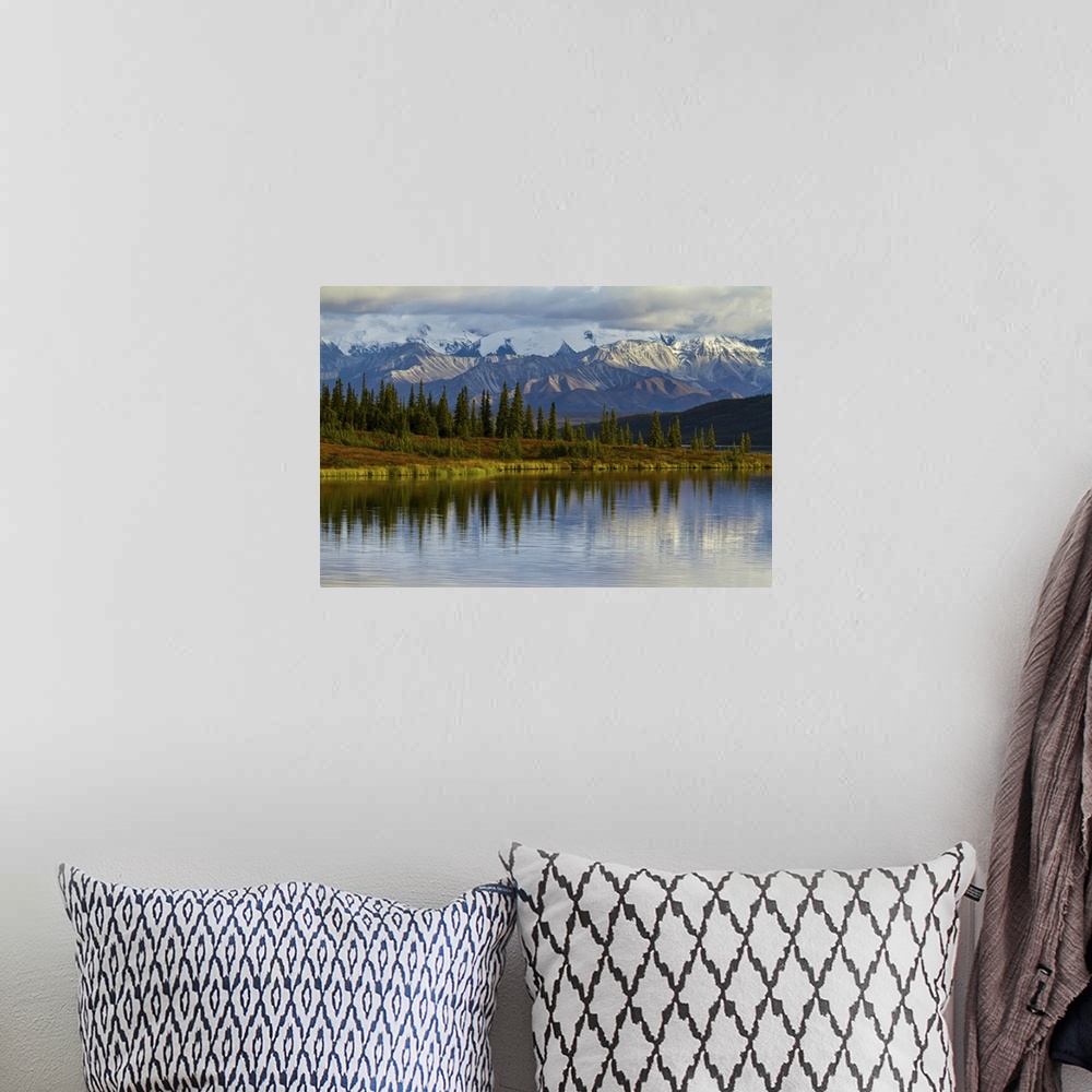 A bohemian room featuring Trees reflected in the surface of Wonder Lake in Denali National Park.