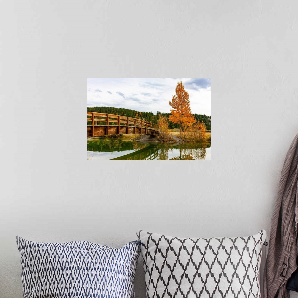 A bohemian room featuring Wooden footbridge over a tranquil pond in autumn, Banff National Park; Banff, Alberta, Canada
