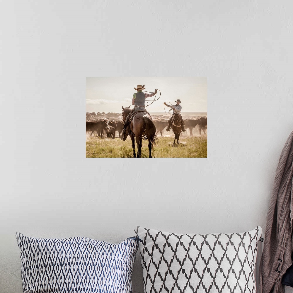 A bohemian room featuring Photograph of two cowboys with their lassos in the air while herding cattle.