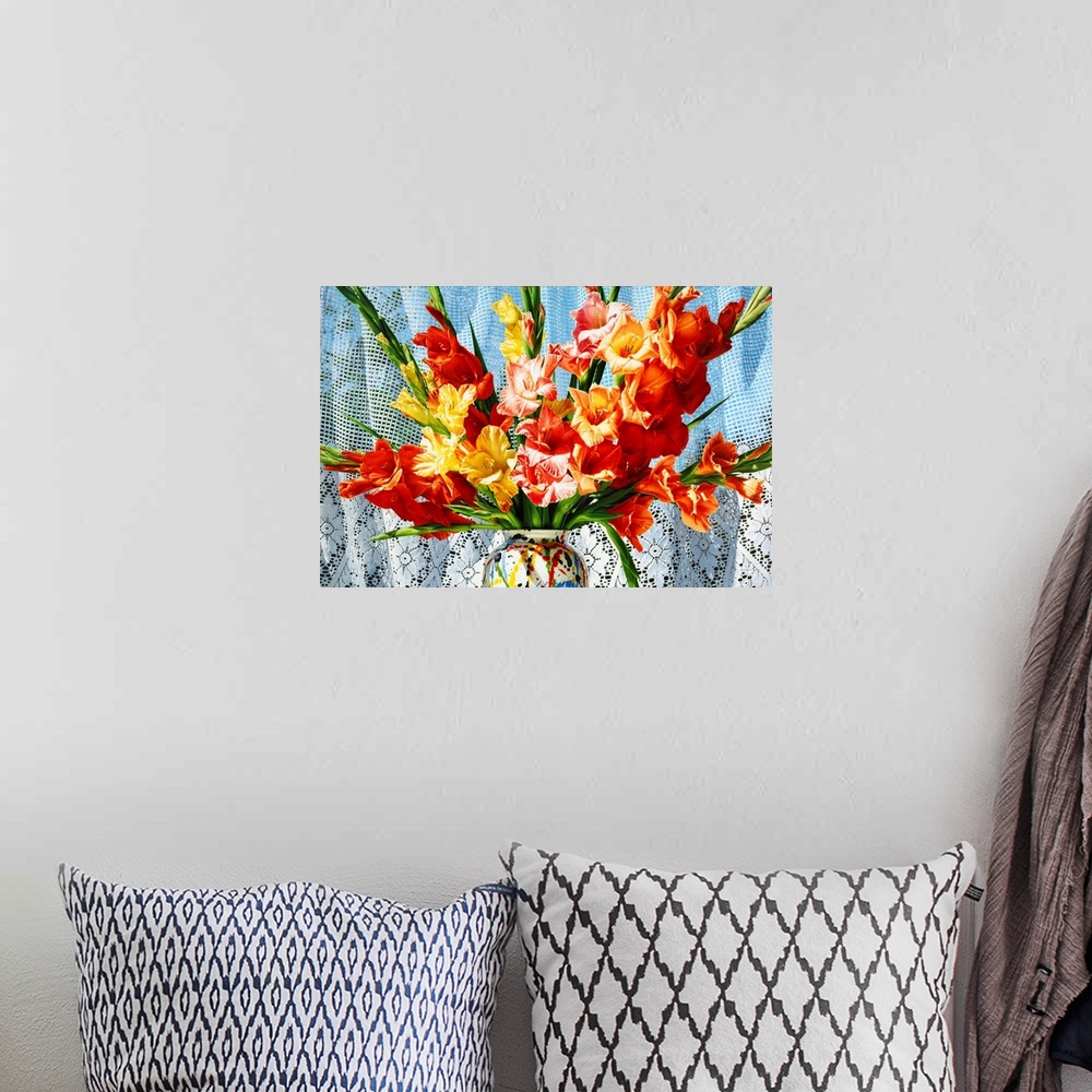 A bohemian room featuring Contemporary vivid realistic still-life painting of bright red orange and yellow flowers in a mul...