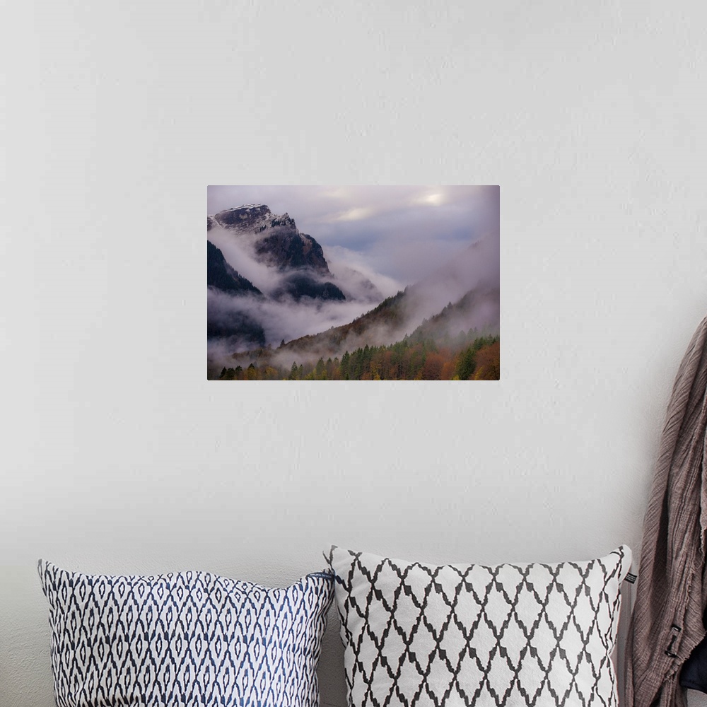 A bohemian room featuring A photograph of a mountain valley covered in deep with thick fog shrouding the area.