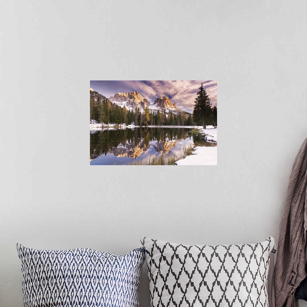 A bohemian room featuring A photograph of a mountain range and forest reflected in still water, under purple clouds.