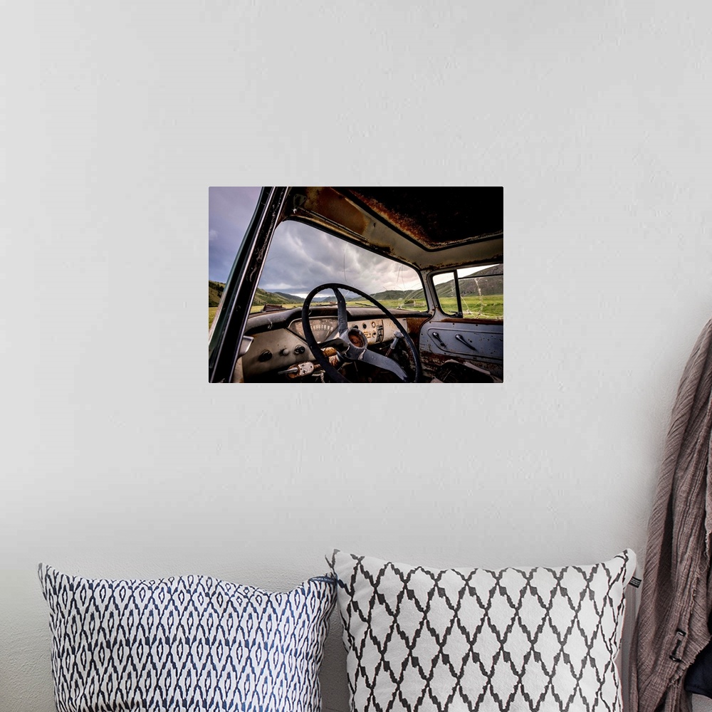 A bohemian room featuring Photograph of the inside of an old abandoned car full of rust in the middle of a valley.