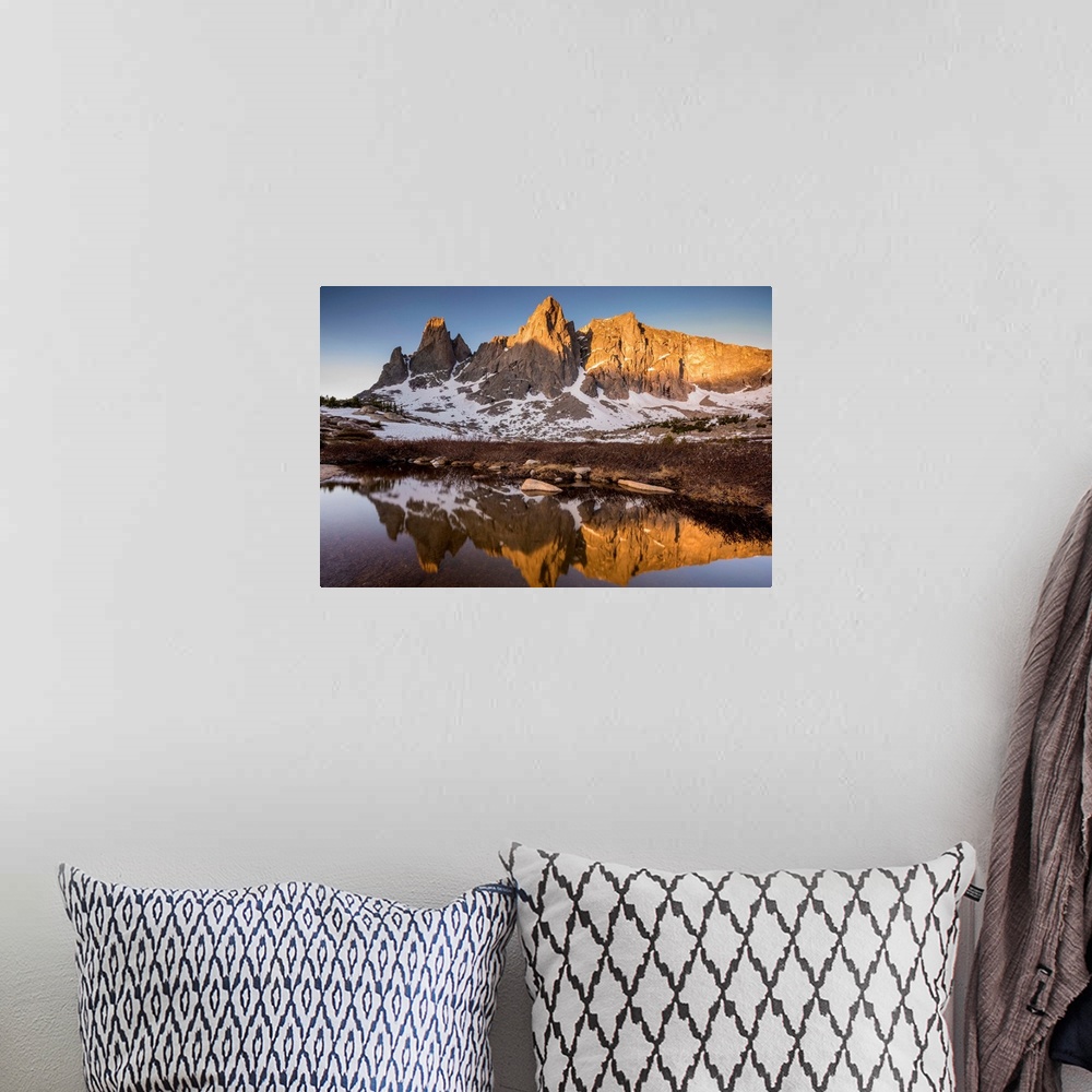 A bohemian room featuring Landscape photograph of a rocky mountain range covered in snow reflecting onto still water.