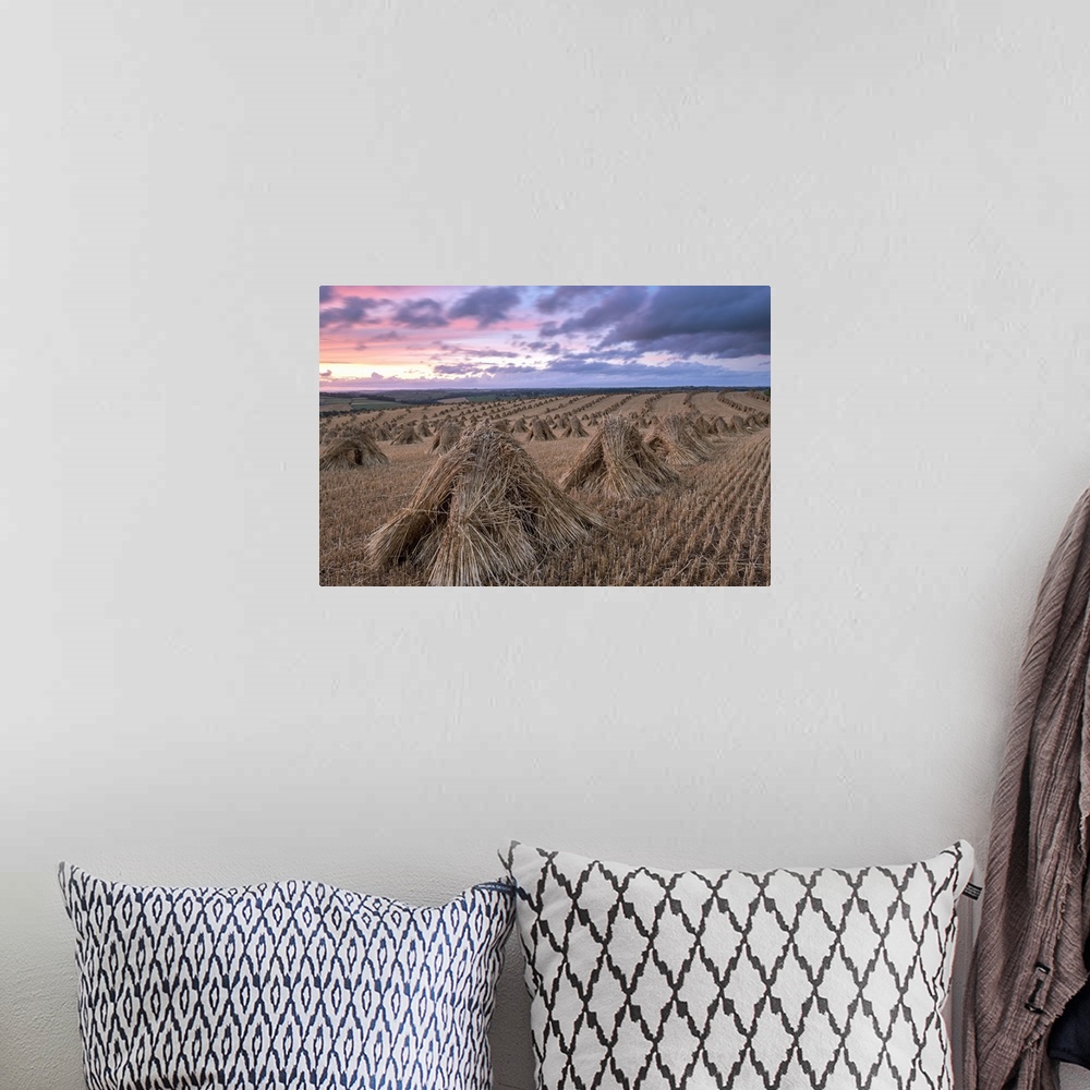 A bohemian room featuring Haystacks in a field under a sky with pink and purple sunset light.