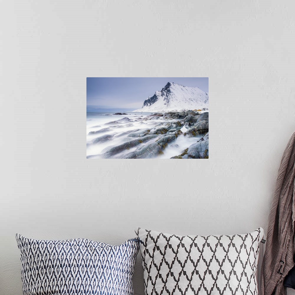 A bohemian room featuring A photograph of a snow covered mountain seen from a rocky shoreline with motion blurred water cau...