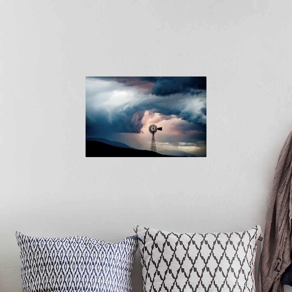 A bohemian room featuring Landscape photograph with a silhouetted windmill amongst rolling hills and a dramatic cloudy sky.
