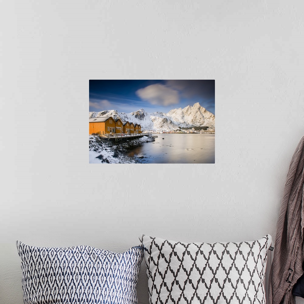 A bohemian room featuring A photograph of a Norwegian yellow cabin village seen with a mountain covered in snow in the back...