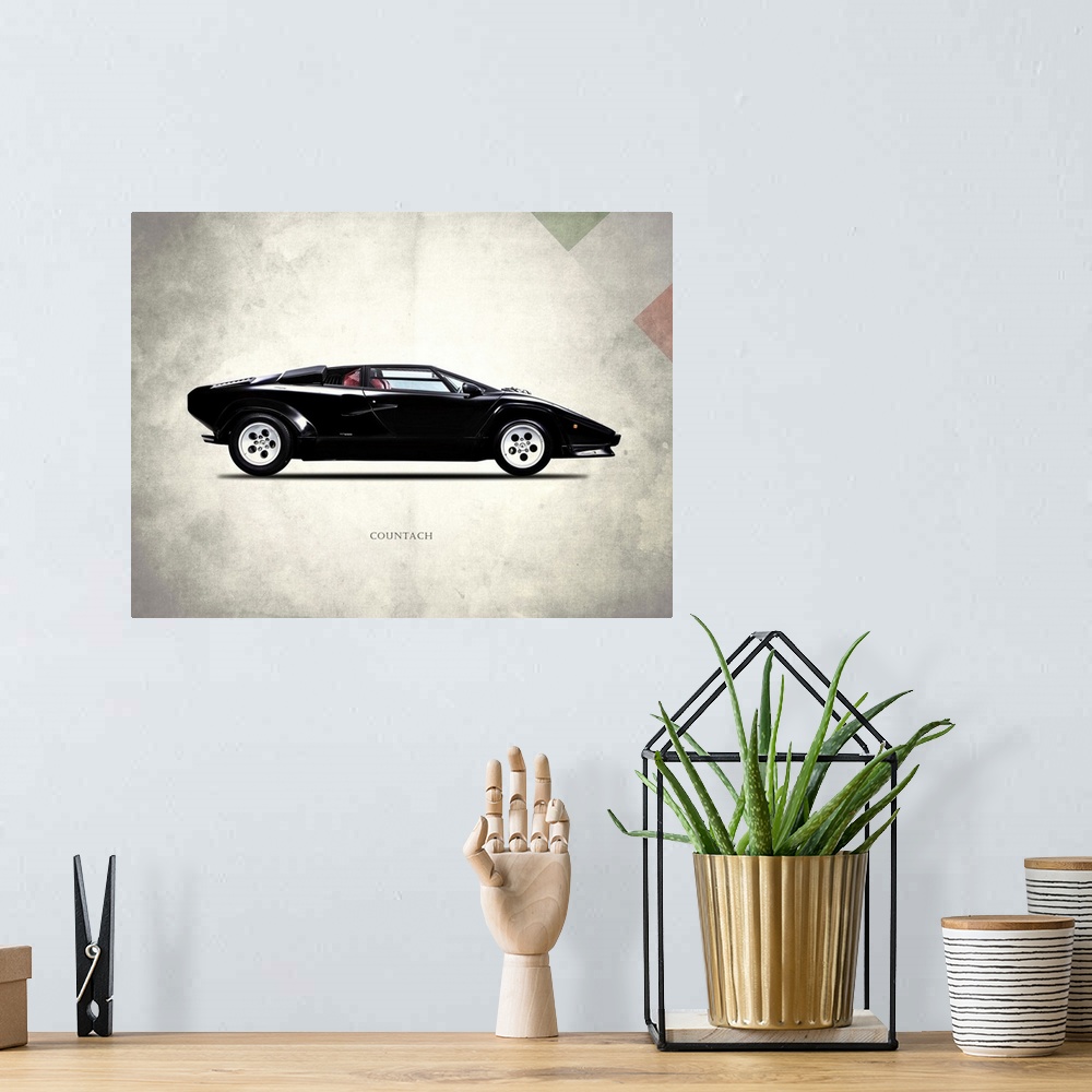 A bohemian room featuring Photograph of a black Lamborghini Countach 5000 printed on a distressed white and gray background...
