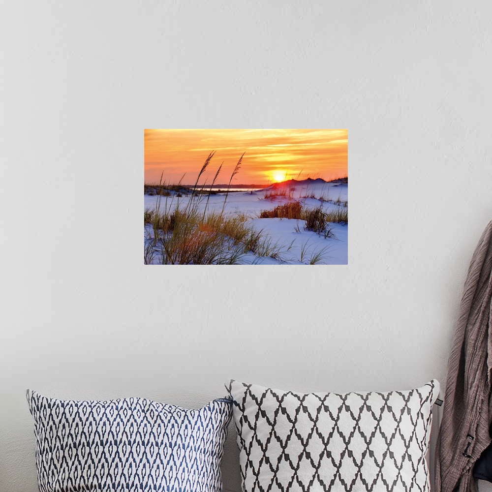 A bohemian room featuring Photograph of a orange and yellow sunset over sandy dunes on a beach.