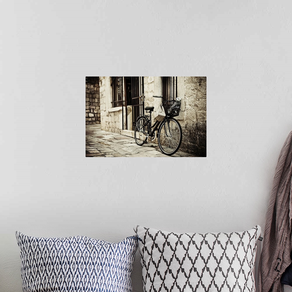 A bohemian room featuring Old bicycle with basket and shopping bag parked in the narrow cobble street.